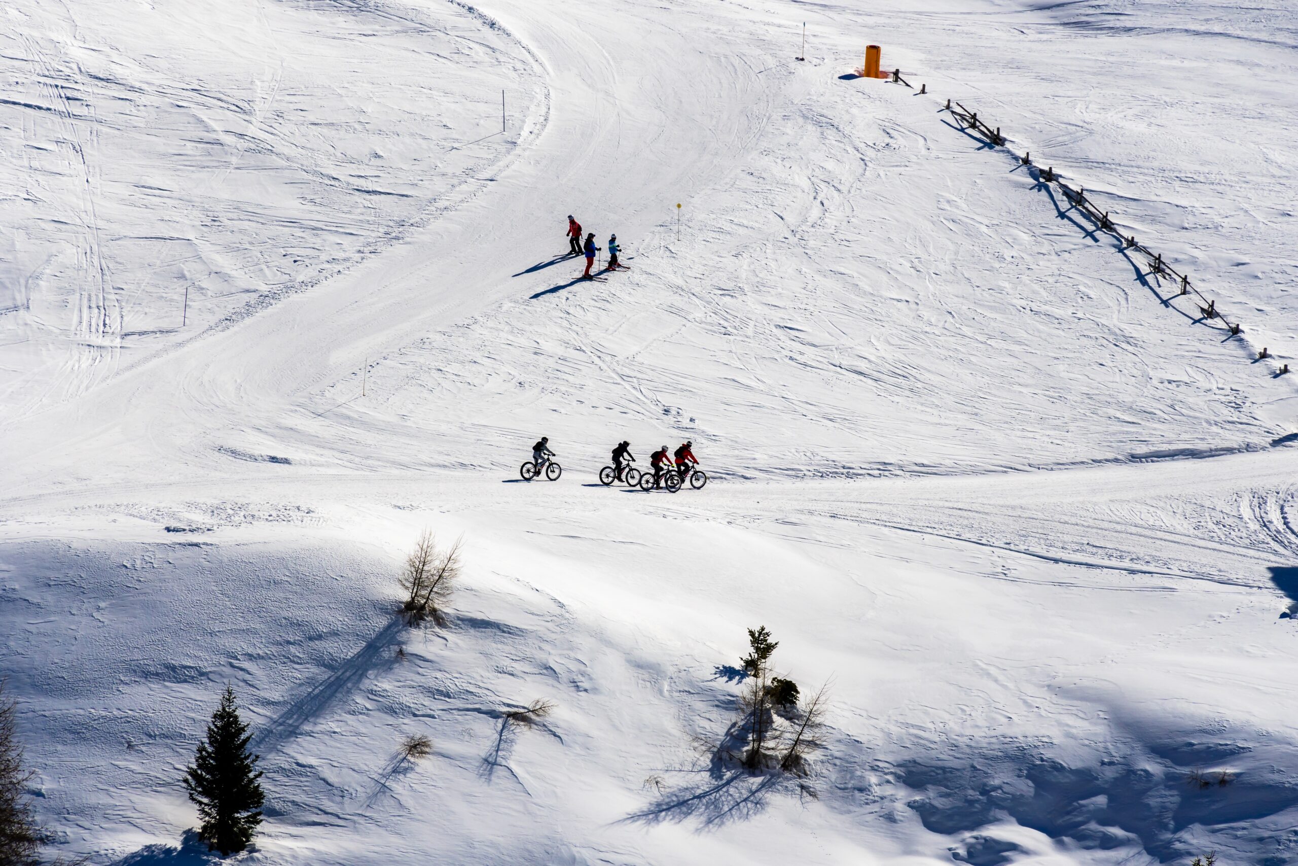 A beautiful view of people cycling and skiing across snowy mountains in South Tyrol, Dolomites, Italy